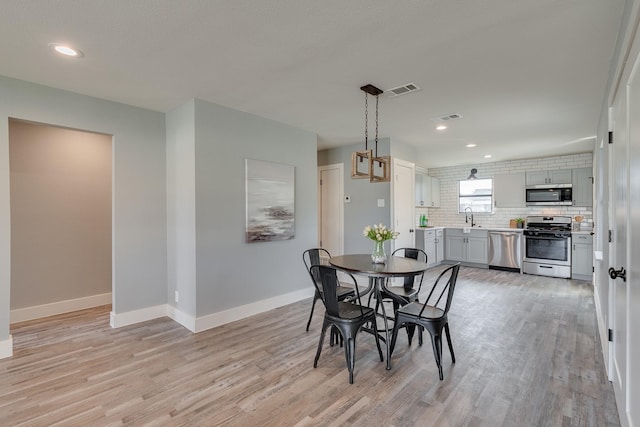 dining area featuring light wood-type flooring and sink