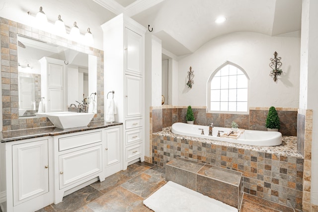 bathroom with crown molding, a relaxing tiled tub, and vanity