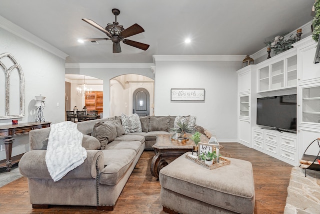 living room featuring dark wood-type flooring, ornamental molding, and ceiling fan with notable chandelier