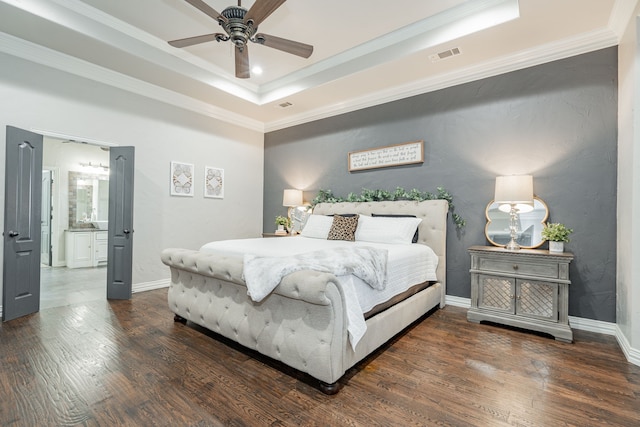 bedroom with ornamental molding, dark hardwood / wood-style flooring, and a tray ceiling