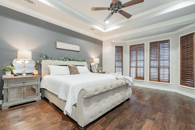 bedroom featuring dark hardwood / wood-style flooring, a tray ceiling, and crown molding