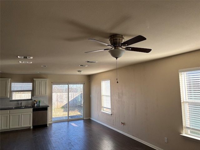 unfurnished living room featuring ceiling fan, dark hardwood / wood-style flooring, plenty of natural light, and sink