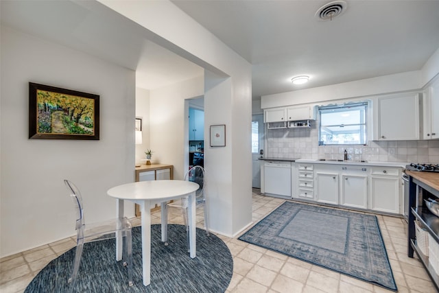 kitchen with sink, backsplash, white cabinets, and dishwasher