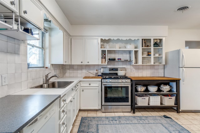 kitchen with light tile patterned floors, backsplash, white appliances, white cabinets, and sink