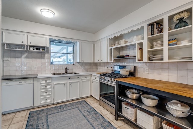 kitchen featuring wooden counters, stainless steel range with gas cooktop, white dishwasher, white cabinets, and sink