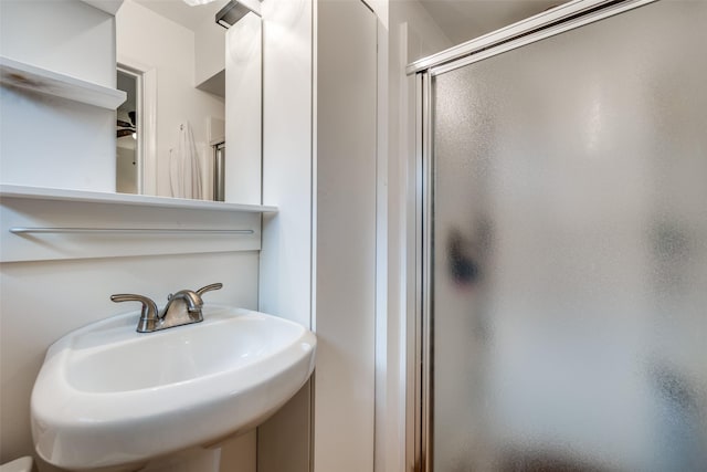 bathroom featuring a shower with shower door and sink