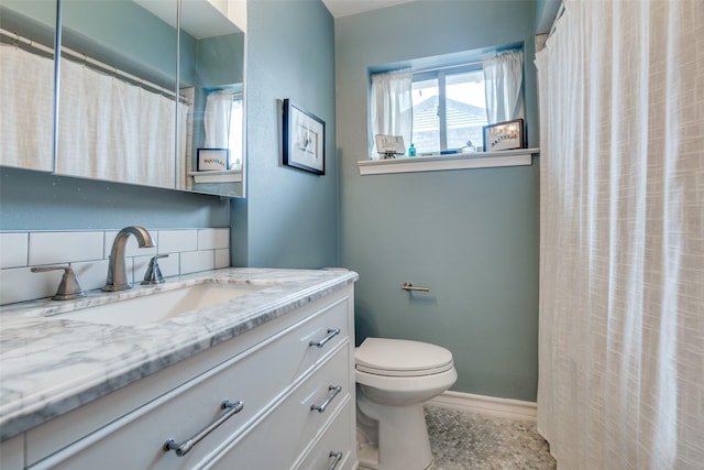 bathroom with toilet, vanity, walk in shower, and tasteful backsplash