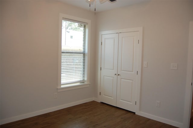 unfurnished bedroom featuring ceiling fan, a closet, and dark hardwood / wood-style flooring