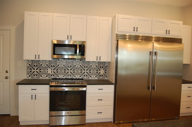 kitchen with dark wood-type flooring, stainless steel appliances, decorative backsplash, and white cabinets