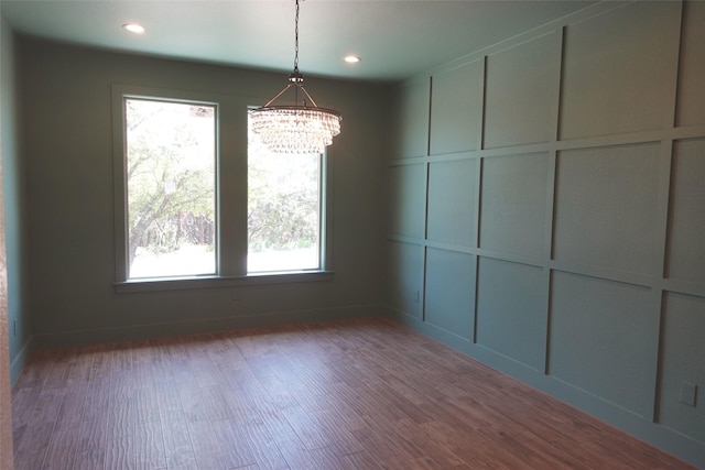 unfurnished dining area featuring hardwood / wood-style flooring, a notable chandelier, and a healthy amount of sunlight