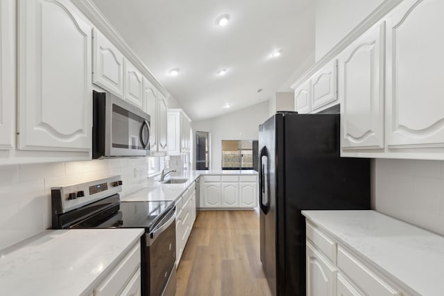 kitchen featuring sink, white cabinetry, vaulted ceiling, appliances with stainless steel finishes, and light hardwood / wood-style floors