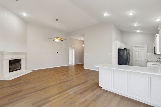 kitchen with black refrigerator, tasteful backsplash, white cabinetry, ceiling fan, and kitchen peninsula