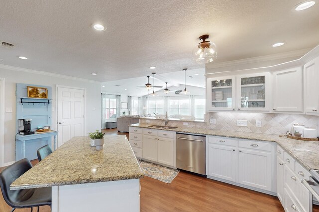 kitchen with appliances with stainless steel finishes, pendant lighting, white cabinets, and light wood-type flooring