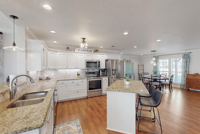 kitchen featuring white cabinetry, sink, stainless steel appliances, and a kitchen island