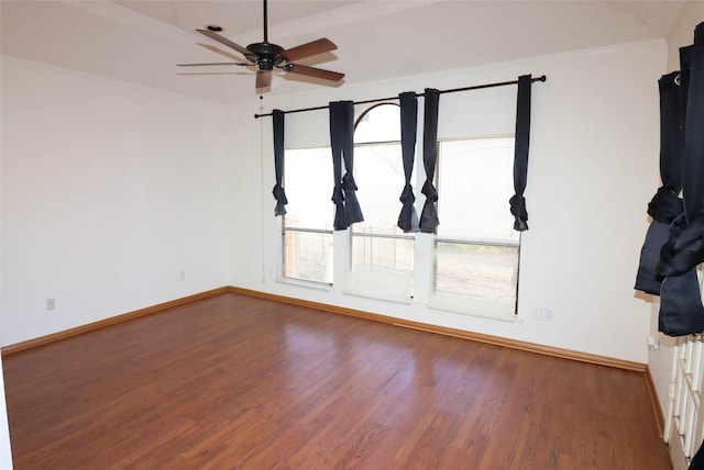 unfurnished room with ceiling fan, dark wood-type flooring, and crown molding