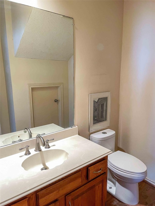 bathroom with wood-type flooring, toilet, and vanity