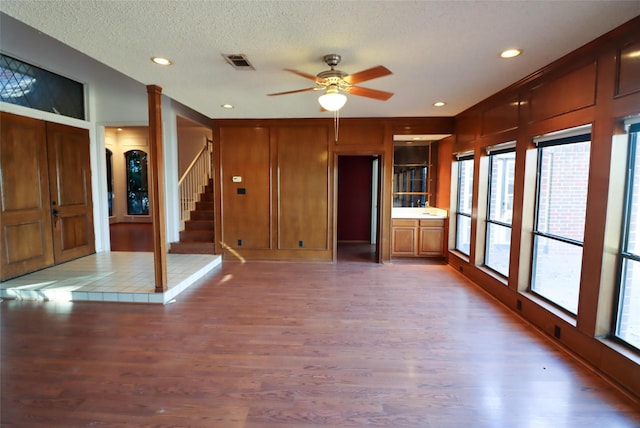 unfurnished living room with wood-type flooring, a textured ceiling, and ceiling fan