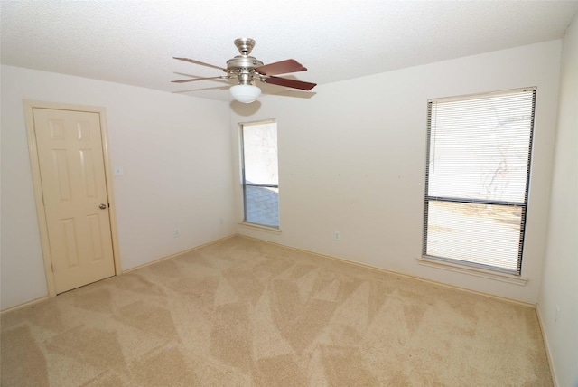 carpeted empty room featuring plenty of natural light, a textured ceiling, and ceiling fan