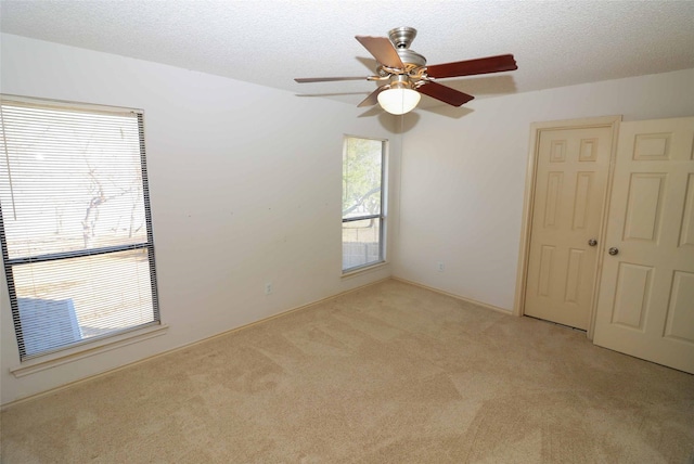 spare room featuring a textured ceiling and light carpet