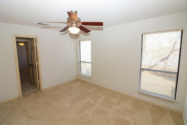 empty room with a textured ceiling, plenty of natural light, and light colored carpet