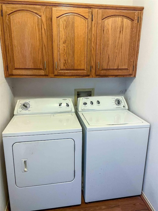 laundry area featuring hardwood / wood-style floors, cabinets, and washing machine and dryer