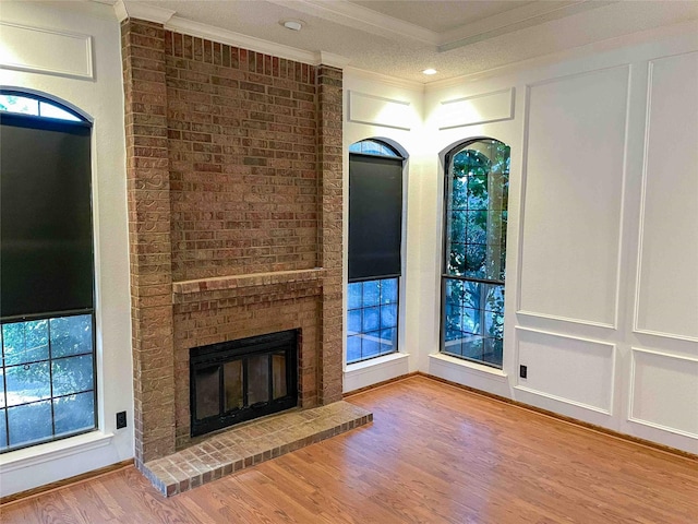 unfurnished living room featuring a brick fireplace, wood-type flooring, and crown molding