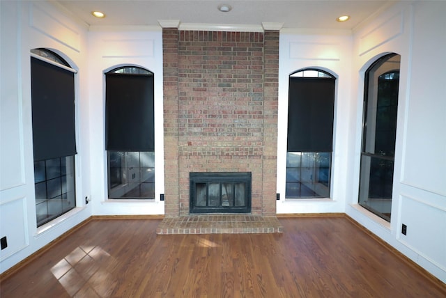 unfurnished living room featuring dark hardwood / wood-style floors, ornamental molding, and a fireplace