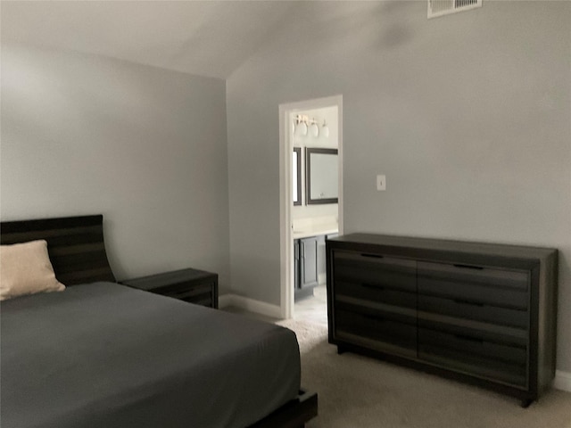 carpeted bedroom with ensuite bathroom and lofted ceiling