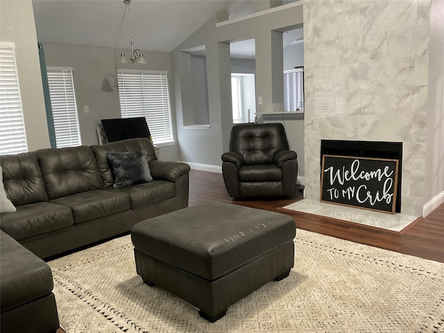 living room with vaulted ceiling, a high end fireplace, hardwood / wood-style floors, and a notable chandelier