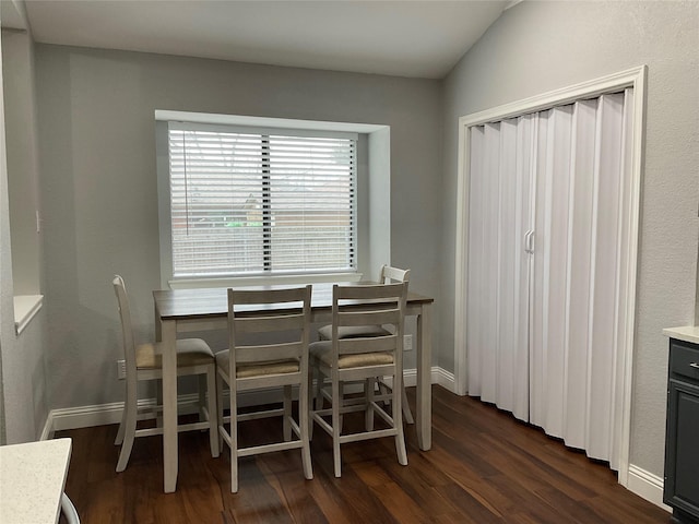 dining area featuring vaulted ceiling and dark wood-type flooring