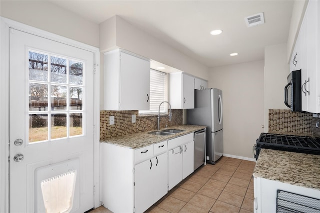 kitchen with decorative backsplash, sink, white cabinetry, stainless steel appliances, and light tile patterned floors