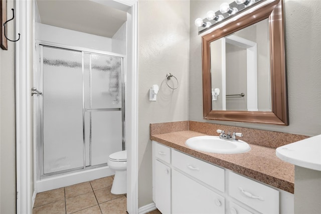 bathroom with an enclosed shower, vanity, toilet, and tile patterned flooring