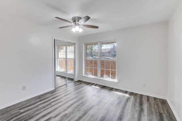 spare room featuring dark wood finished floors, a ceiling fan, and baseboards