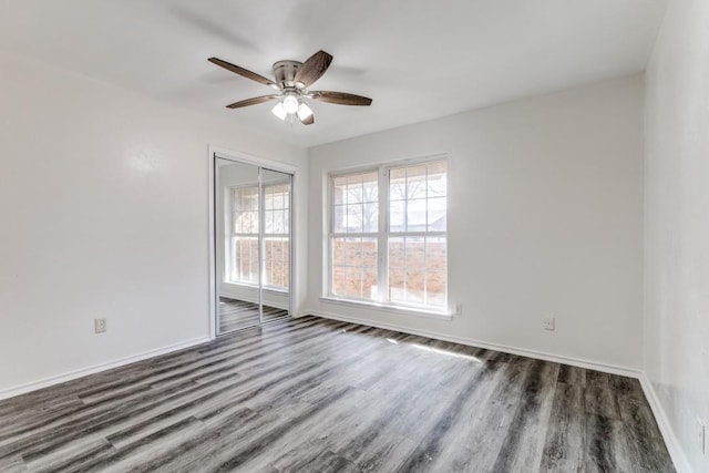 unfurnished room with dark wood-style floors, ceiling fan, and baseboards