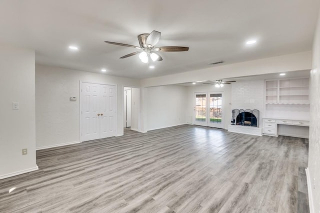 unfurnished living room with ceiling fan, a brick fireplace, and light hardwood / wood-style flooring