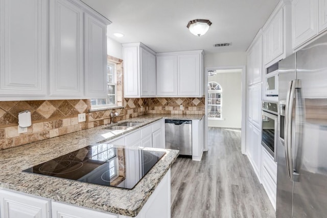 kitchen featuring visible vents, white cabinets, light stone counters, appliances with stainless steel finishes, and a sink