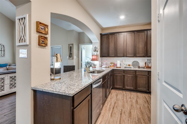 kitchen with light wood-type flooring, light stone countertops, stainless steel dishwasher, dark brown cabinetry, and sink