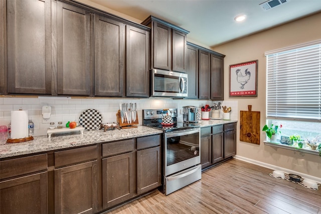 kitchen with stainless steel appliances, light hardwood / wood-style floors, dark brown cabinetry, and light stone countertops