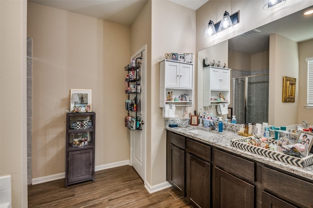 bathroom with hardwood / wood-style flooring, walk in shower, and vanity