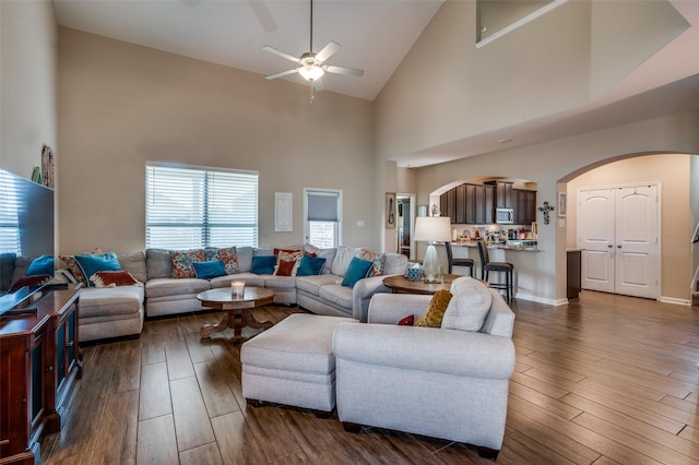 living room with ceiling fan, dark hardwood / wood-style flooring, and a high ceiling