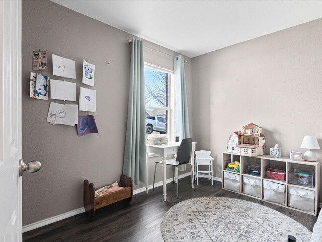 game room featuring wood finished floors, a textured wall, and baseboards