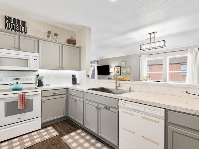 kitchen with white appliances, decorative light fixtures, dark hardwood / wood-style flooring, sink, and gray cabinetry