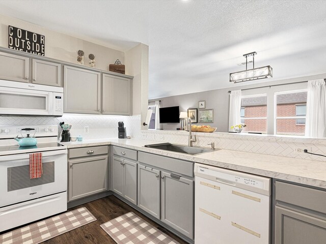 kitchen with gray cabinets, white appliances, backsplash, and a sink