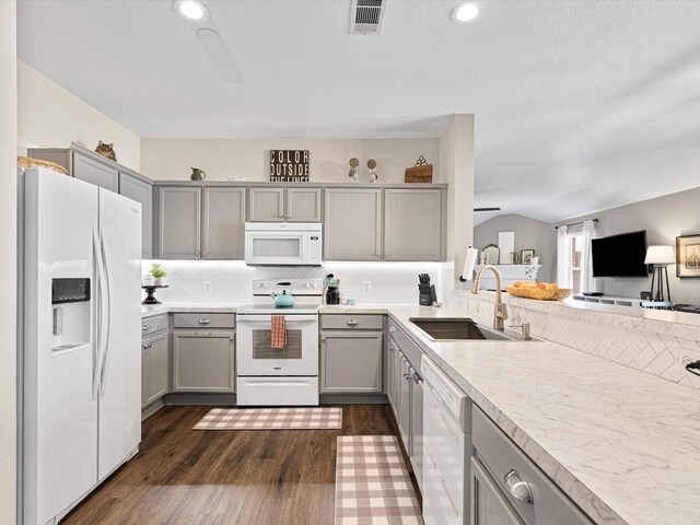 kitchen with a sink, white appliances, dark wood finished floors, and gray cabinets