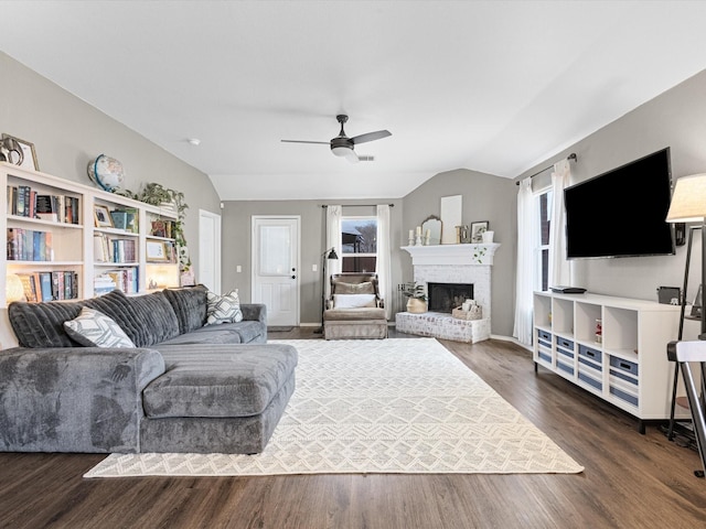 living room featuring ceiling fan, a brick fireplace, dark wood-type flooring, and lofted ceiling