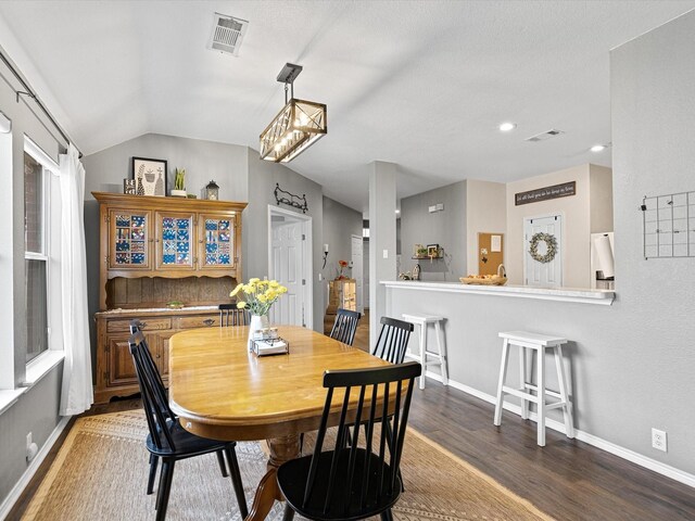dining room with baseboards, visible vents, wood finished floors, and lofted ceiling