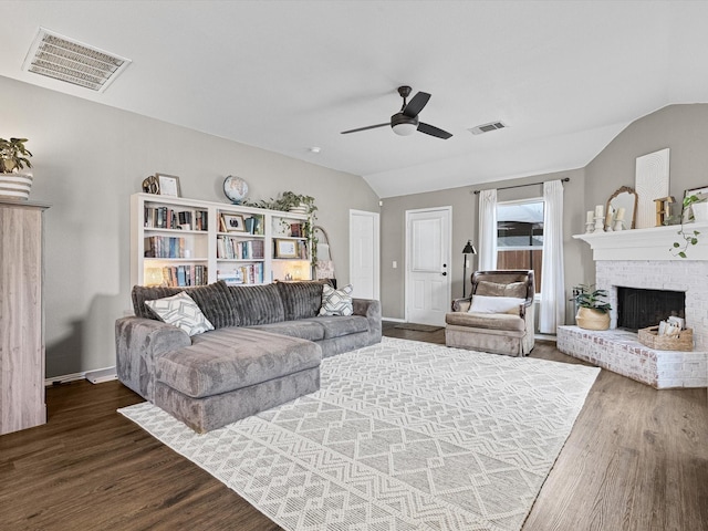 living room featuring ceiling fan, dark wood-type flooring, lofted ceiling, and a fireplace