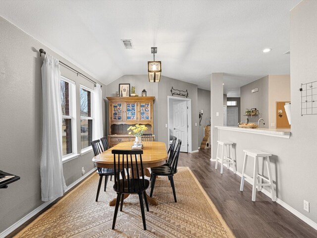 dining space featuring vaulted ceiling, visible vents, dark wood-style floors, and baseboards