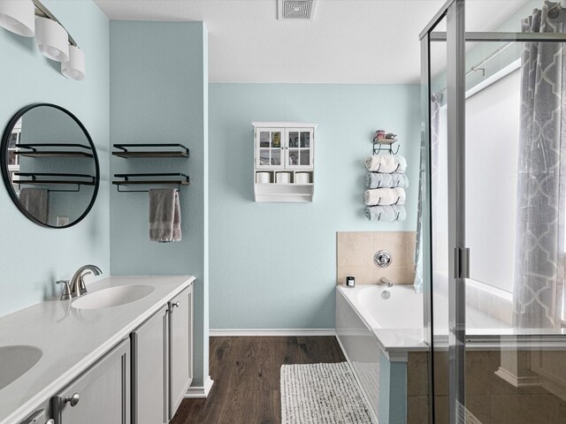 bathroom with a shower stall, a sink, visible vents, baseboards, and wood finished floors