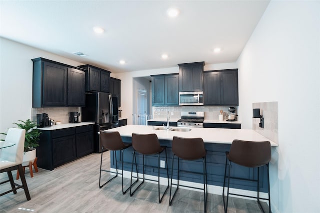 kitchen with decorative backsplash, sink, light hardwood / wood-style flooring, a breakfast bar area, and stainless steel appliances